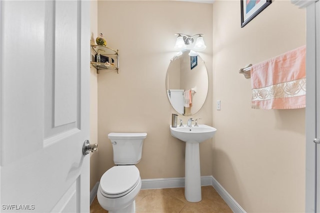 half bath featuring baseboards, toilet, and tile patterned flooring