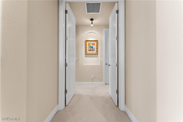corridor featuring baseboards, visible vents, and light colored carpet