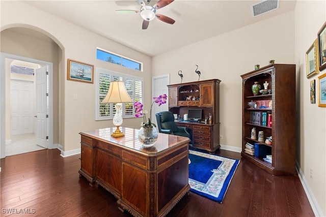 home office with visible vents, baseboards, arched walkways, dark wood-style flooring, and a ceiling fan