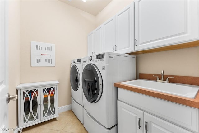 laundry room featuring light tile patterned flooring, washing machine and clothes dryer, cabinet space, and a sink