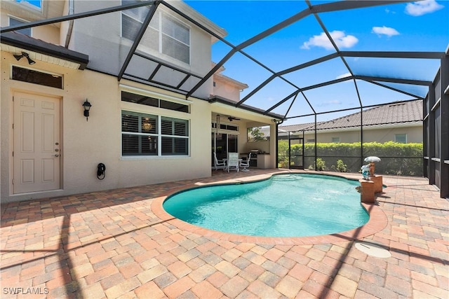 view of swimming pool with a patio, glass enclosure, a ceiling fan, and a fenced in pool