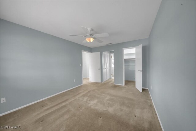 1015 Tropic Ter, North Fort Myers, FL 33903 - unfurnished bedroom featuring a closet, baseboards, a walk in closet, a ceiling fan, and carpet