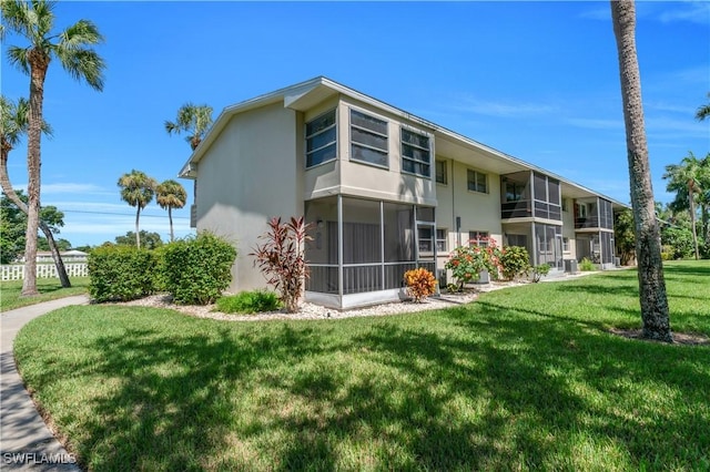 1015 Tropic Ter, North Fort Myers, FL 33903 - back of property featuring a lawn, stucco siding, and a sunroom