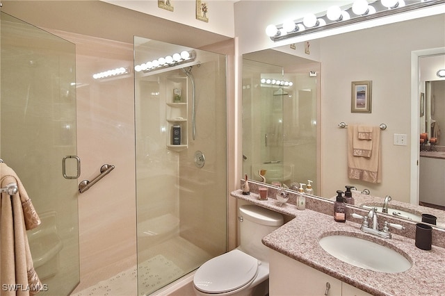 bathroom with toilet, a shower stall, and vanity