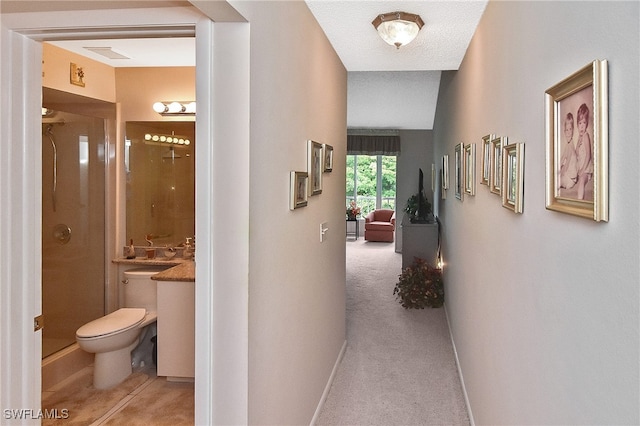 hallway featuring baseboards, light carpet, and visible vents