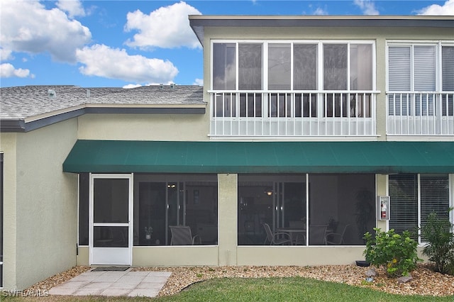 back of house featuring stucco siding and a sunroom