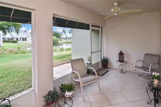 sunroom featuring a water view and ceiling fan