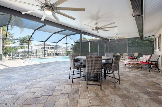 view of patio featuring outdoor dining space, an outdoor pool, a ceiling fan, and glass enclosure