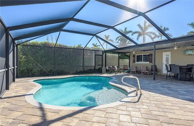 pool with outdoor dining space, ceiling fan, glass enclosure, and a patio area
