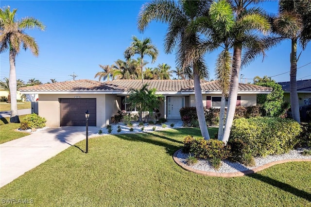 single story home with a tile roof, a front yard, a garage, concrete driveway, and stucco siding
