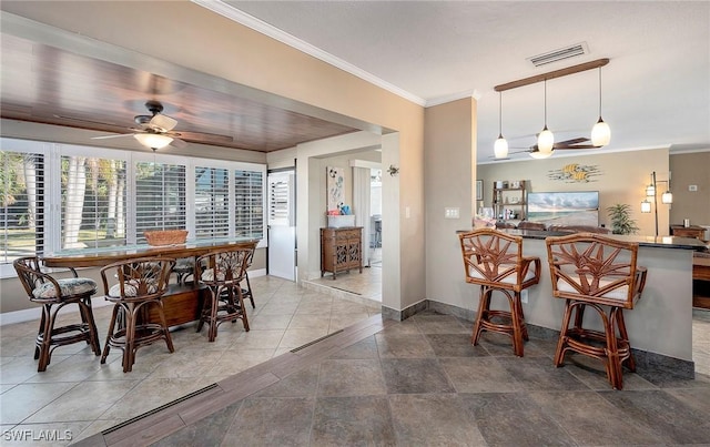dining room with baseboards, visible vents, a ceiling fan, and crown molding