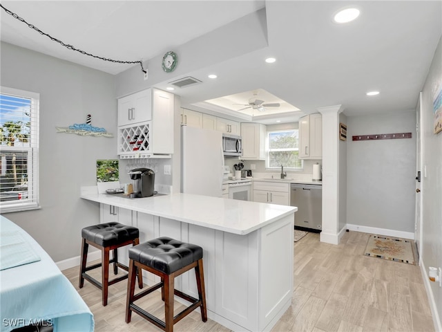 kitchen featuring a sink, light wood-style floors, stainless steel appliances, and a peninsula