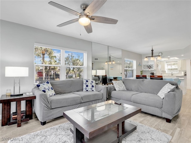 living area featuring light wood-type flooring, a ceiling fan, and visible vents