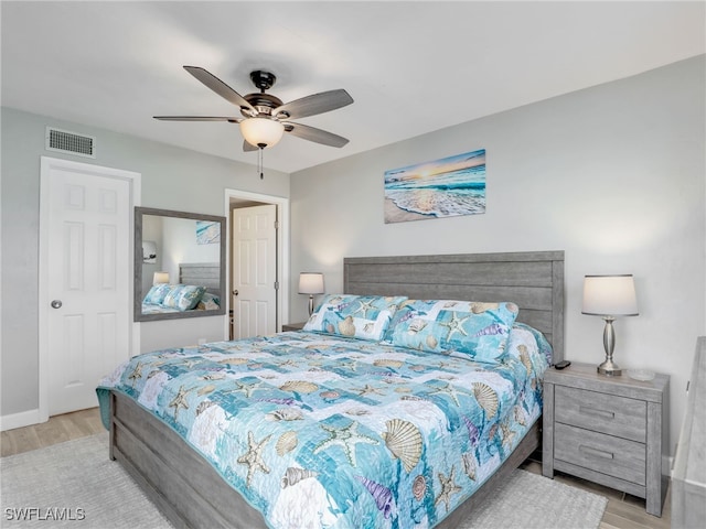 bedroom featuring a ceiling fan, baseboards, visible vents, and light wood finished floors