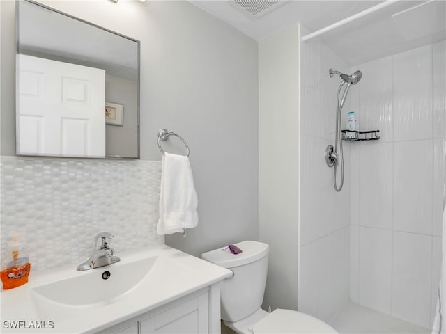 bathroom featuring vanity, tasteful backsplash, toilet, and tiled shower