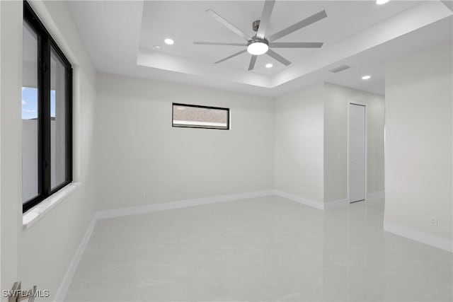 spare room featuring recessed lighting, a ceiling fan, a raised ceiling, and plenty of natural light