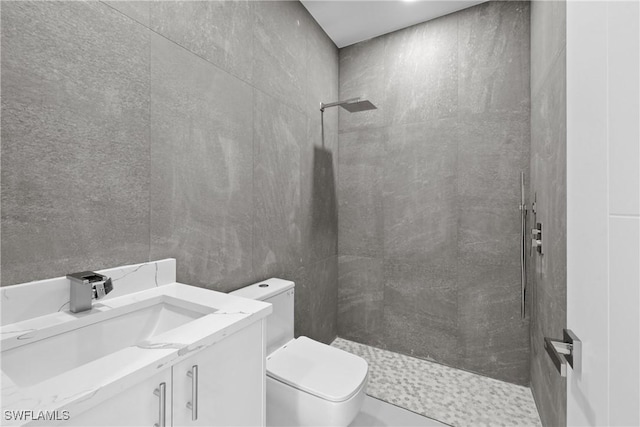 bathroom featuring toilet, a tile shower, and vanity