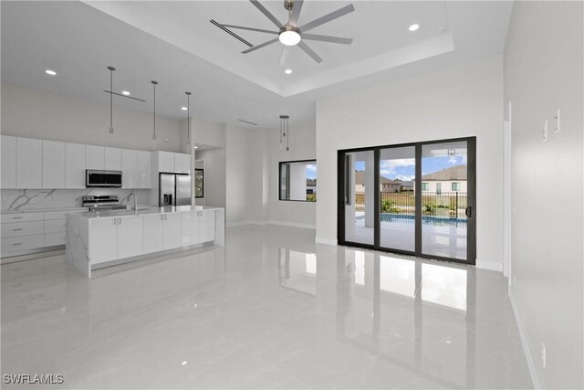 unfurnished living room with a towering ceiling, ceiling fan, recessed lighting, and a sink