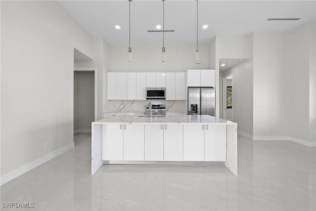kitchen with a large island, light stone counters, white cabinetry, baseboards, and appliances with stainless steel finishes