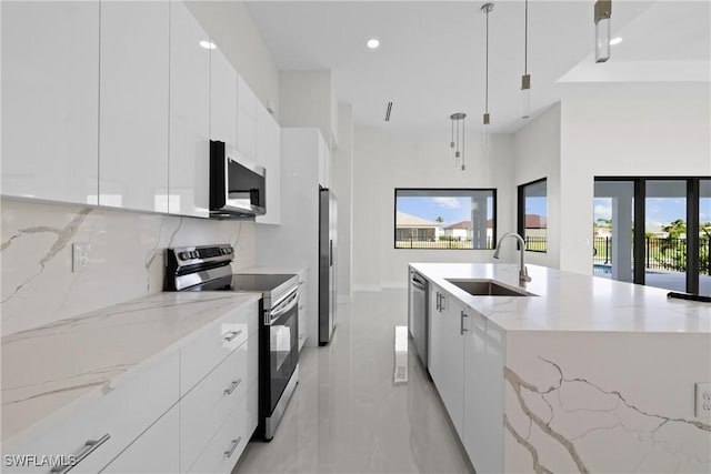 kitchen with stainless steel appliances, decorative light fixtures, white cabinets, a sink, and modern cabinets