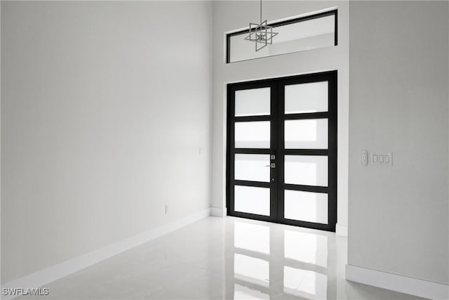 entryway featuring baseboards, a notable chandelier, a high ceiling, and french doors
