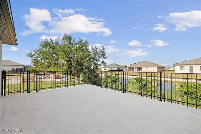 view of patio / terrace with a residential view, a water view, and fence