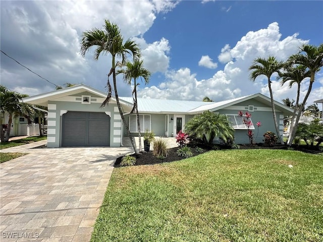 ranch-style house with a garage, stucco siding, a front lawn, and decorative driveway