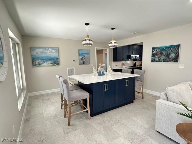 kitchen featuring light countertops, a kitchen breakfast bar, baseboards, stainless steel microwave, and visible vents