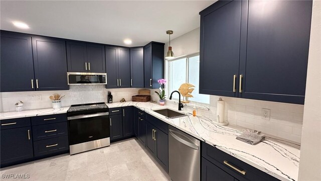 kitchen with a sink, light stone counters, backsplash, and stainless steel appliances
