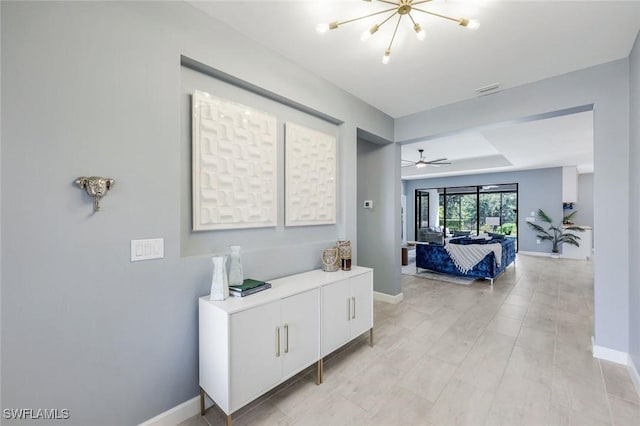 hallway featuring baseboards and a chandelier