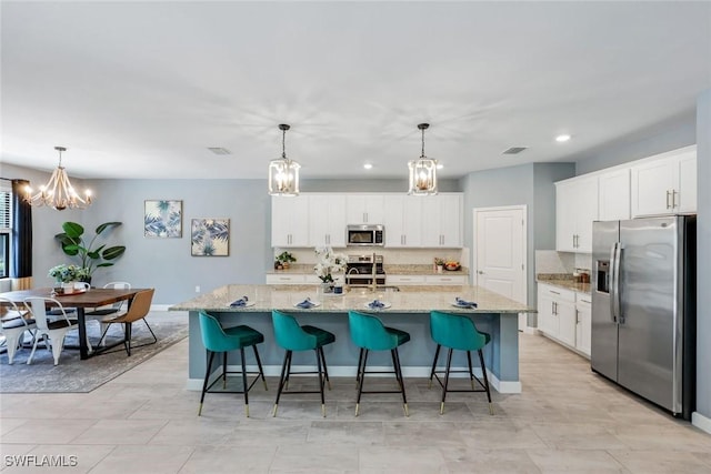 kitchen with white cabinets, appliances with stainless steel finishes, a chandelier, and tasteful backsplash
