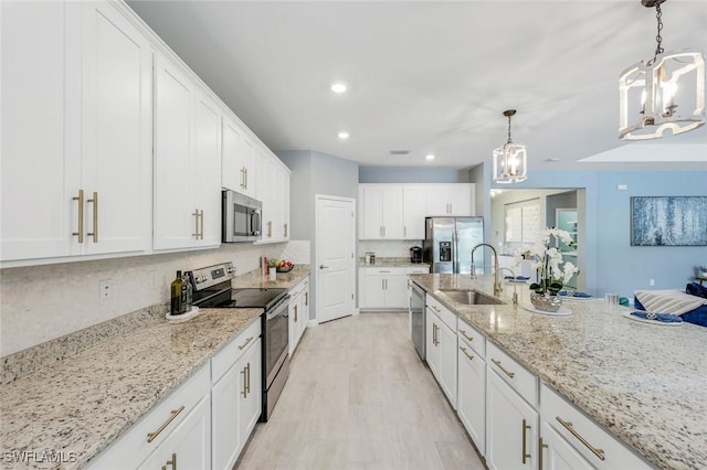 kitchen featuring appliances with stainless steel finishes, tasteful backsplash, a sink, an inviting chandelier, and white cabinetry
