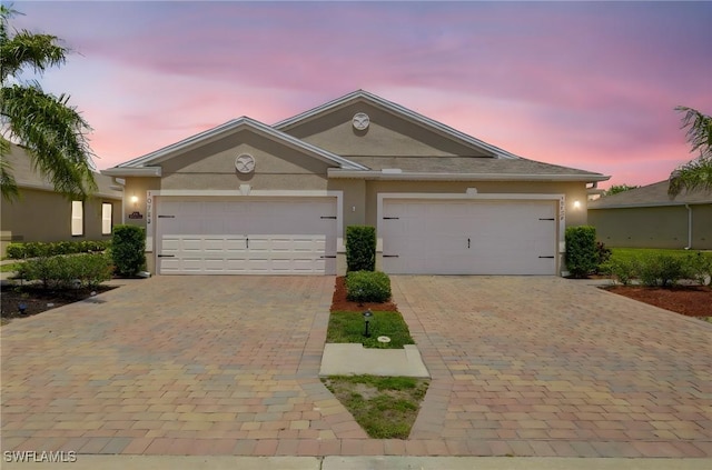 view of front of home featuring decorative driveway, a garage, and stucco siding