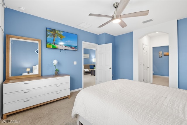 bedroom with ceiling fan, visible vents, arched walkways, baseboards, and light carpet