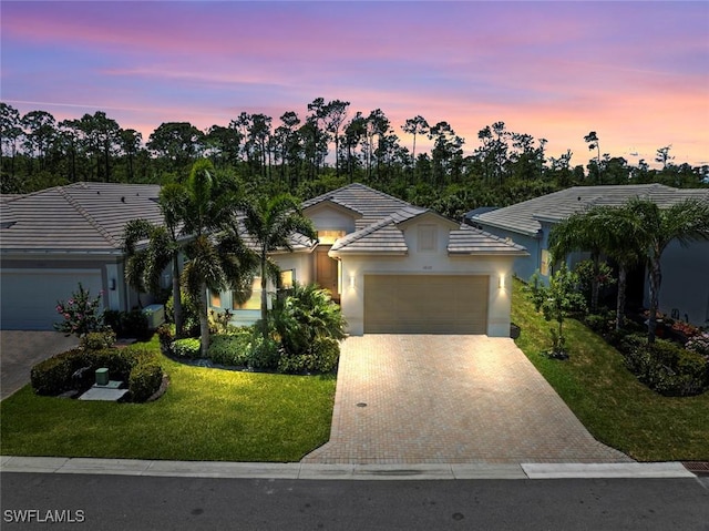 ranch-style home featuring stucco siding, decorative driveway, an attached garage, and a front lawn