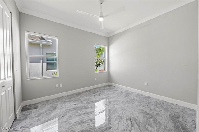 empty room featuring baseboards, a ceiling fan, marble finish floor, and crown molding