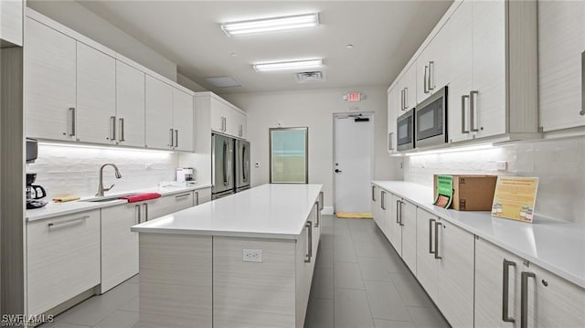 kitchen with light countertops, appliances with stainless steel finishes, a sink, and tasteful backsplash