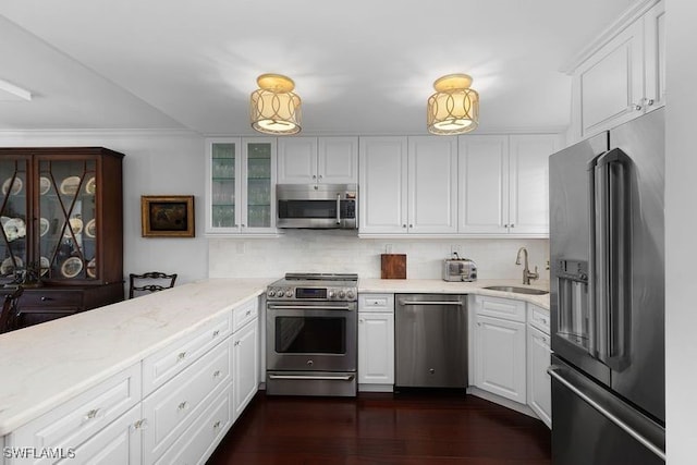 kitchen featuring white cabinetry, decorative backsplash, a sink, stainless steel appliances, and light stone countertops