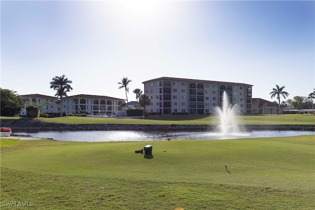 view of community with a lawn, golf course view, and a water view