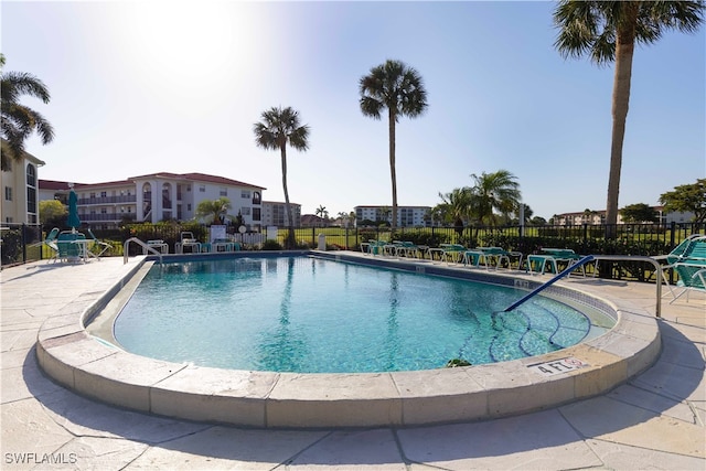 community pool with fence and a patio area