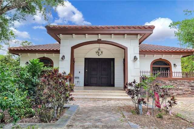 doorway to property featuring stucco siding and a tiled roof