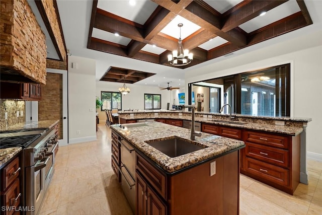 kitchen featuring range with two ovens, an inviting chandelier, a large island with sink, and a sink