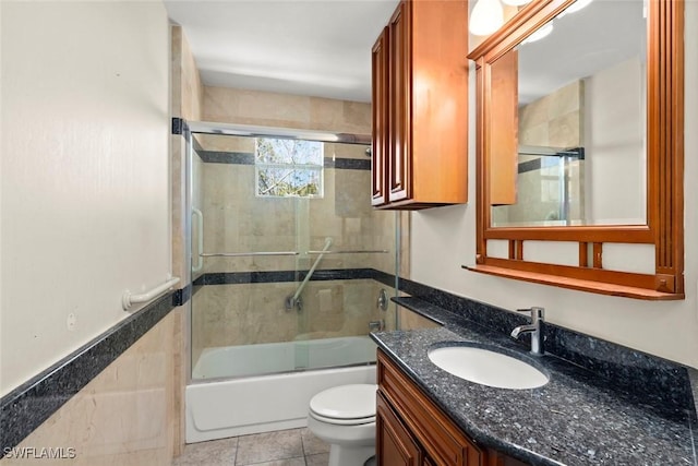 bathroom featuring vanity, bath / shower combo with glass door, tile patterned floors, and toilet