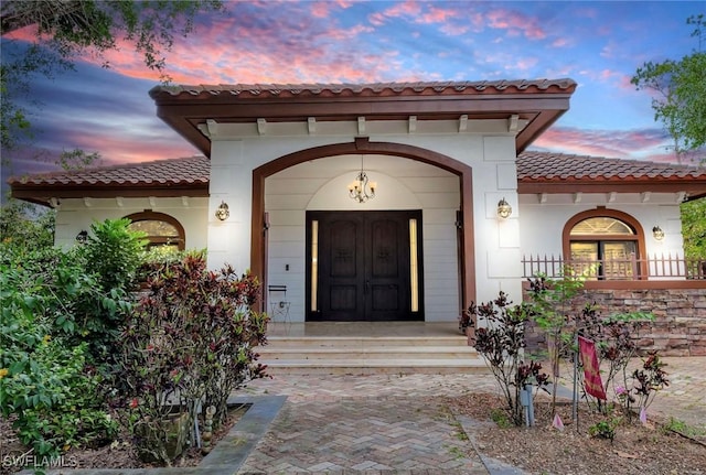 2605 64th St SW, Naples, FL 34105 - exterior entry at dusk featuring stucco siding and a tile roof
