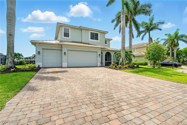 view of front of home featuring stucco siding, decorative driveway, a standing seam roof, and a front lawn