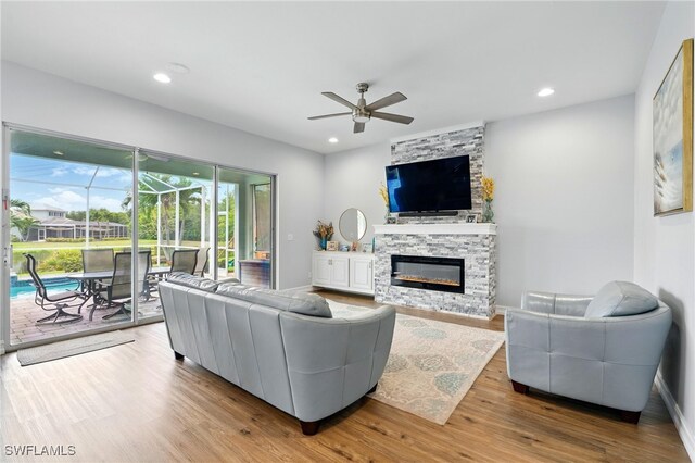 living room featuring ceiling fan, recessed lighting, a sunroom, a fireplace, and wood finished floors