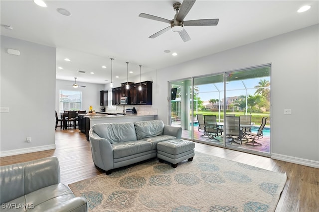 living area with wood finished floors, ceiling fan, recessed lighting, and baseboards