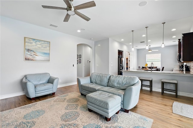 living area with recessed lighting, arched walkways, wood finished floors, ceiling fan, and visible vents