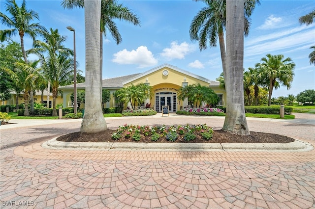 view of front of property featuring french doors, stucco siding, and curved driveway