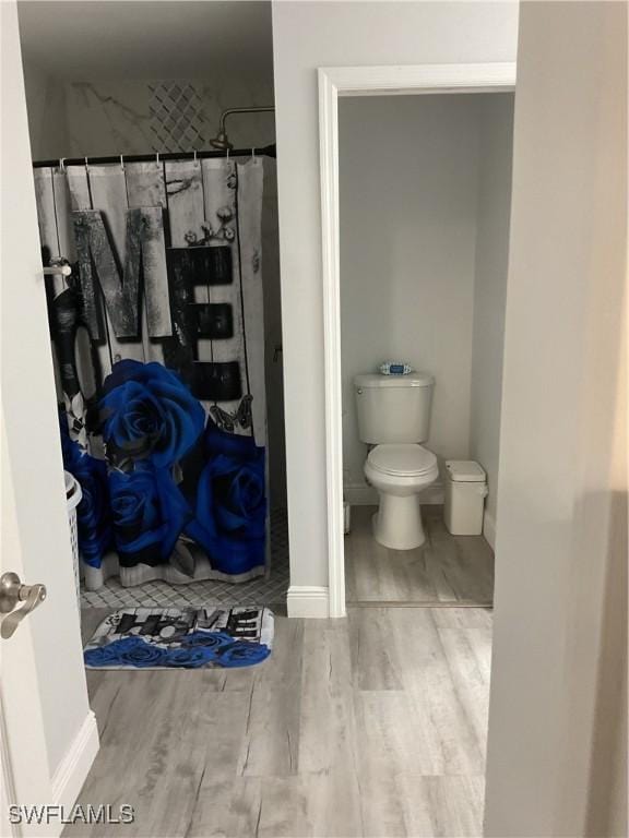 full bathroom with baseboards, wood finished floors, toilet, and a shower with curtain